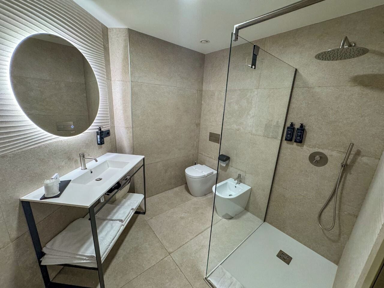 Een moderne badkamer met een douchecabine van glas, een wastafel met spiegel en een toilet.