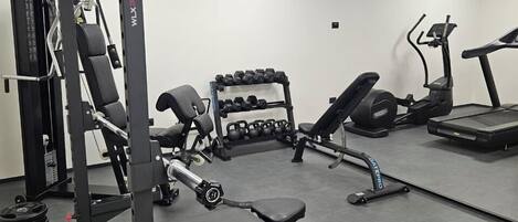 A gym with weightlifting equipment, treadmills, and dumbbells.