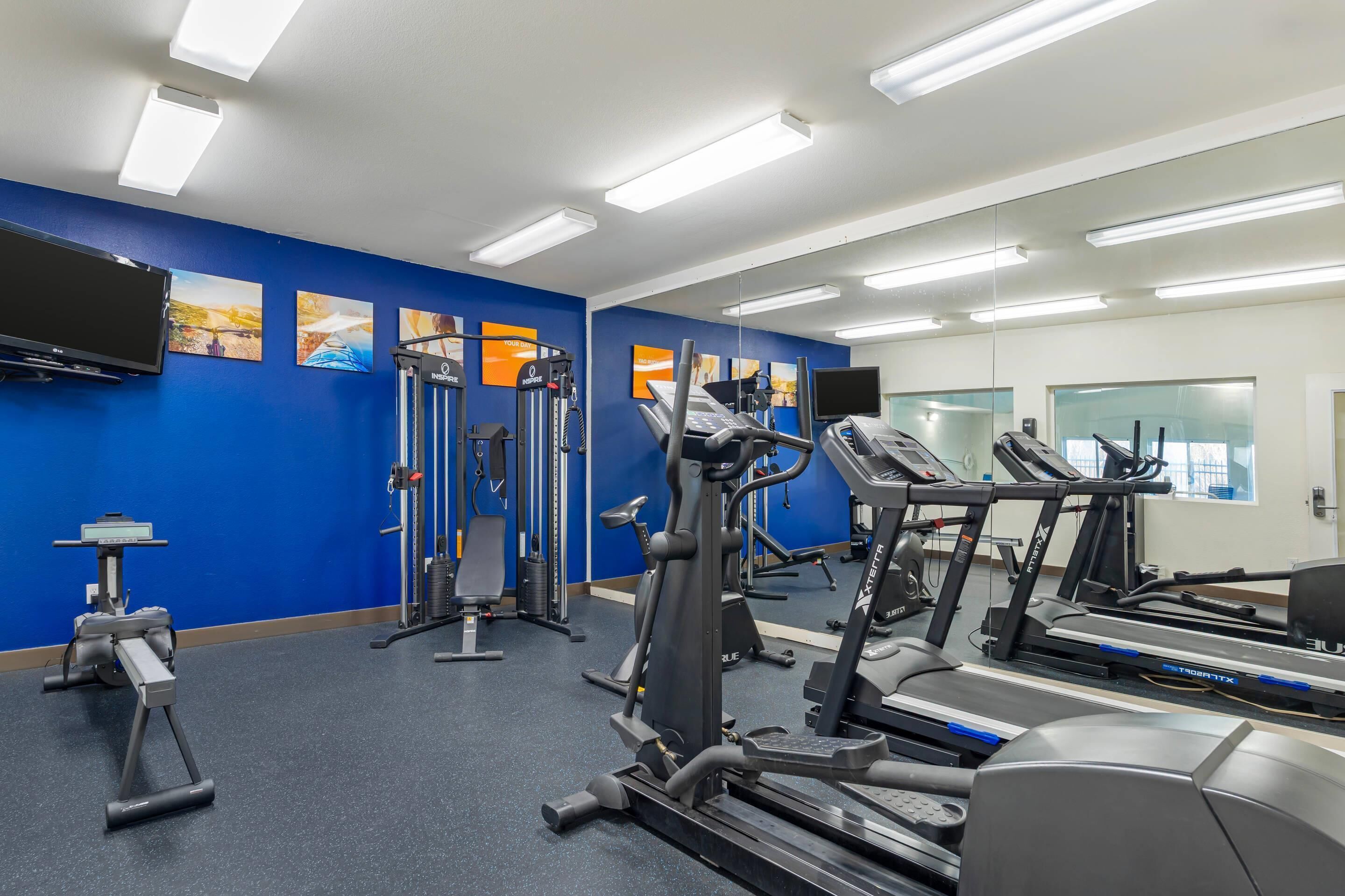 A gym with exercise equipment, a TV, and artwork on the walls.