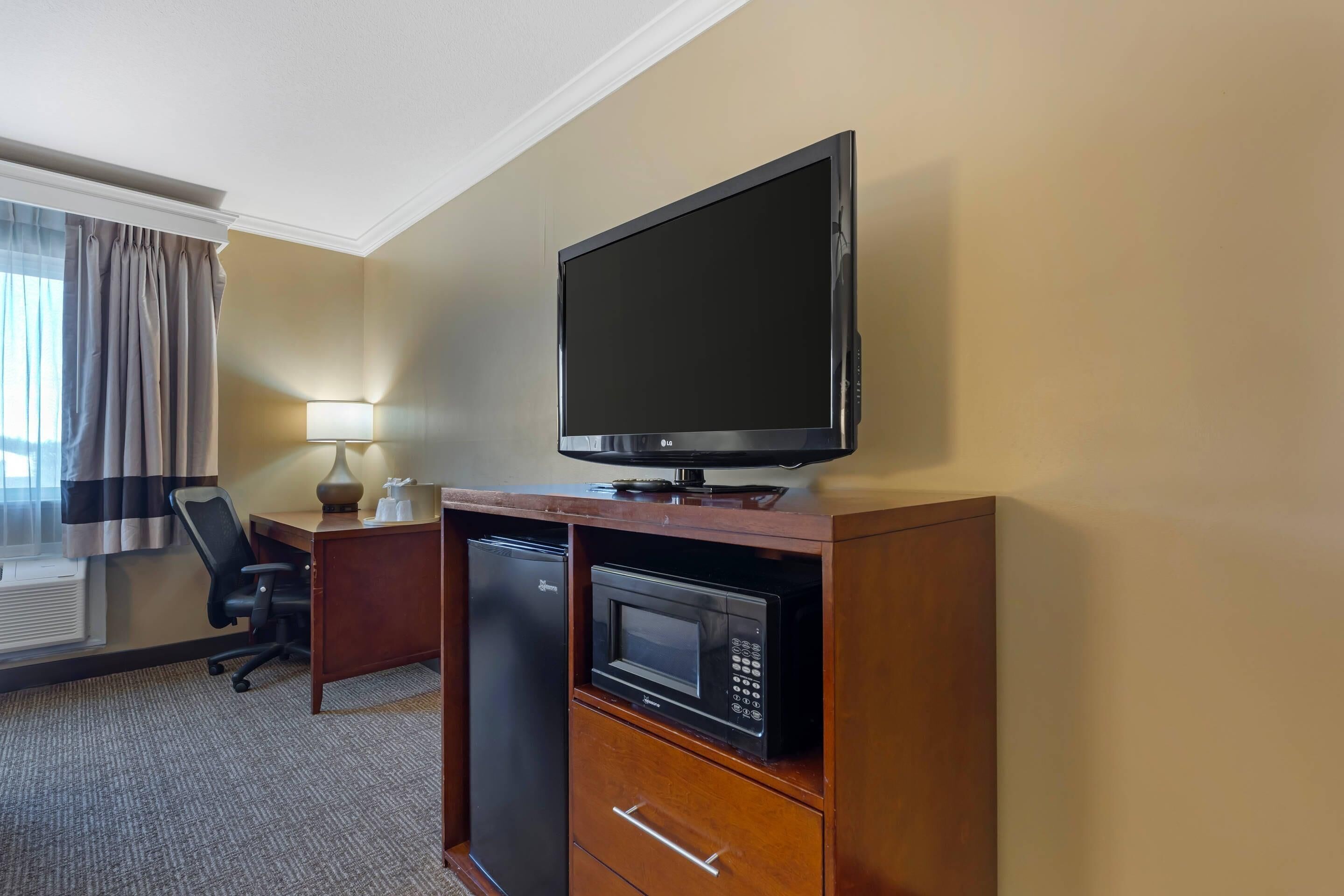 Hotelkamer met flatscreen televisie, magnetron, minibar, bureau, stoel en lamp.