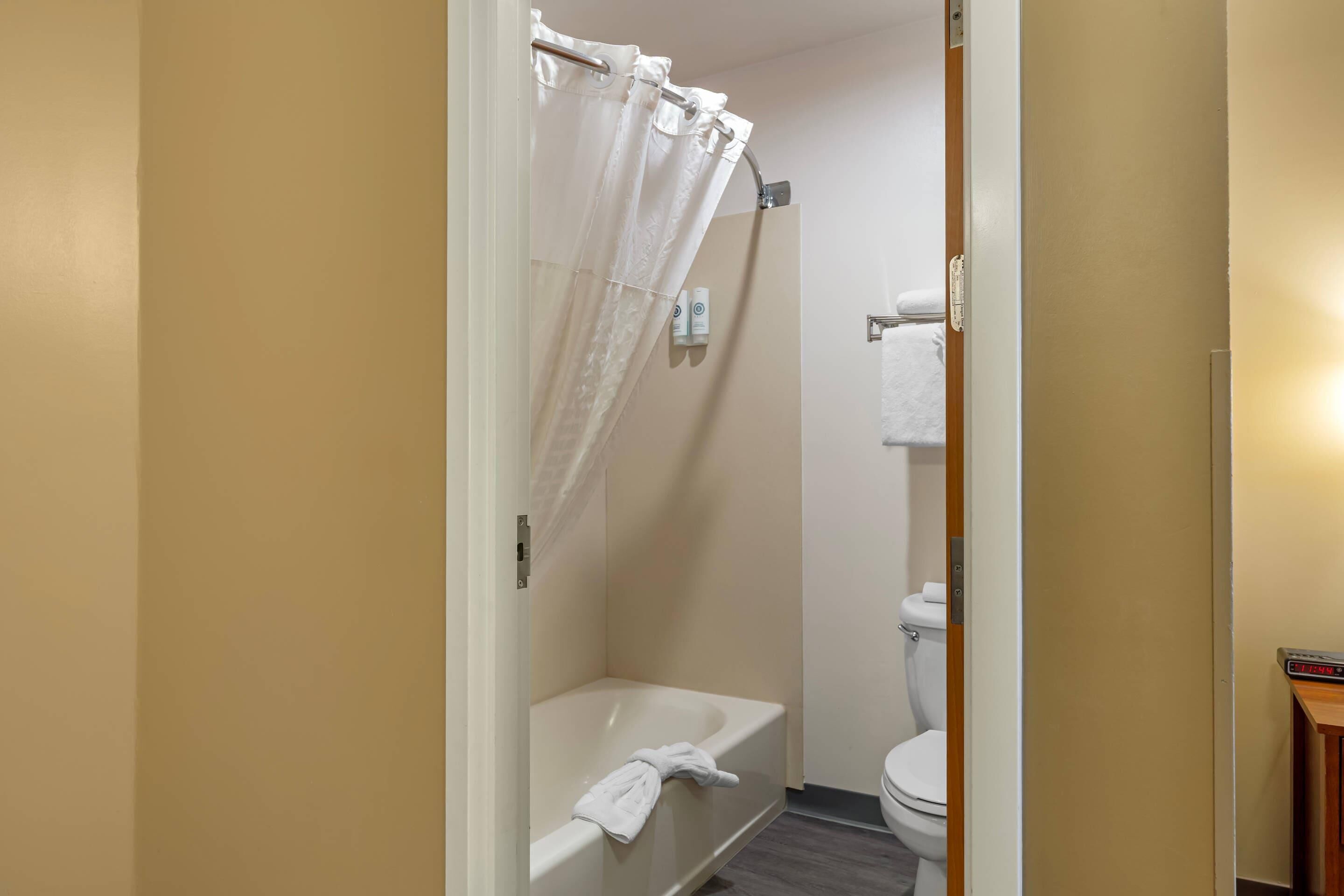 A bathroom with a bathtub, toilet, and shower curtain.