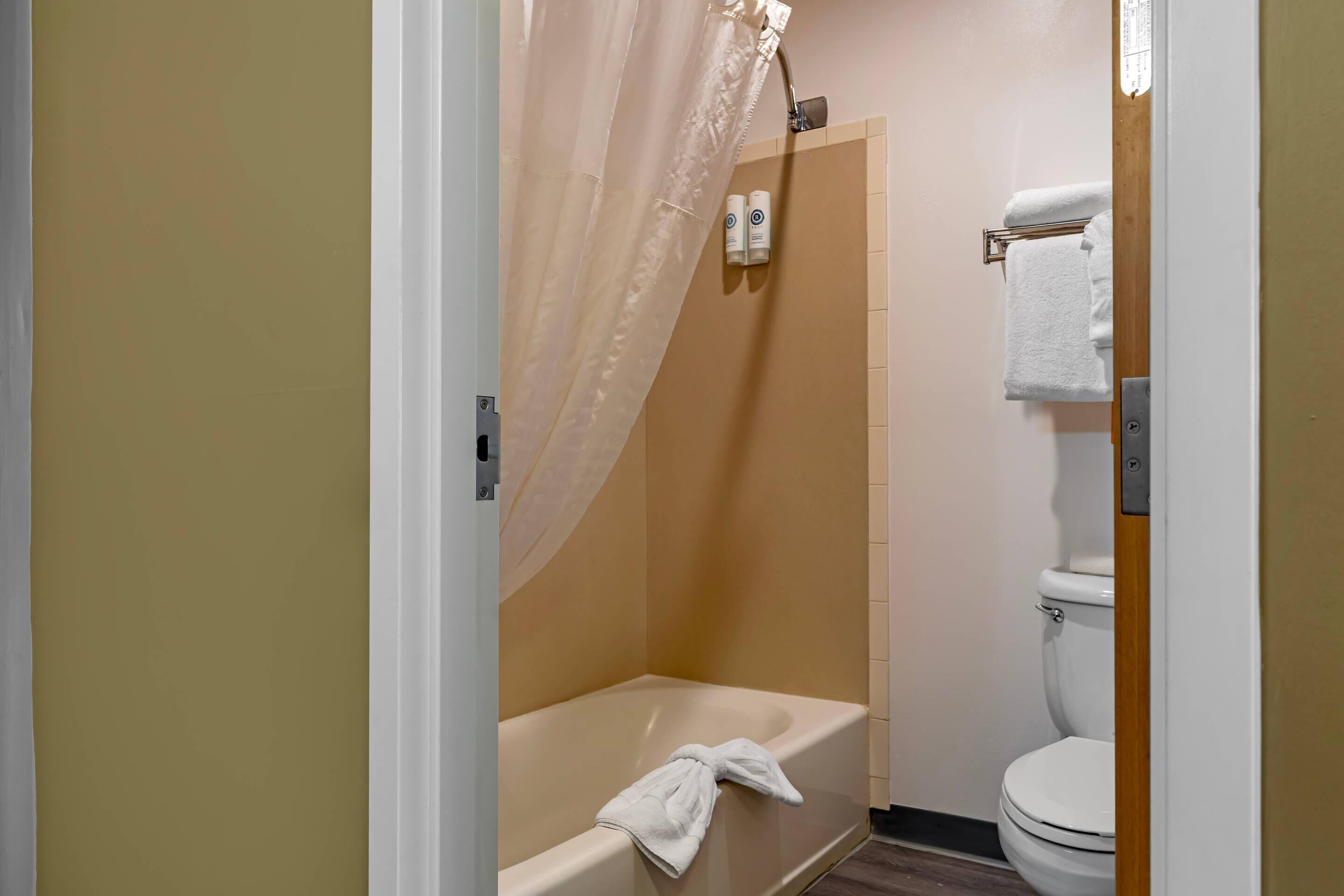 A bathroom with a bathtub, toilet, and shower curtain.