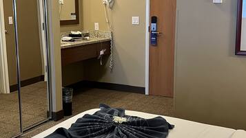 Quarto de hotel com uma cama, banheiro com espelho, secador de cabelo e porta.