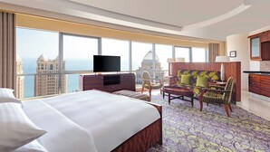 A hotel room with a large bed, a TV, a sofa, and a view of a cityscape. - Qabila Westbay Hotel by Marriott (Doha)