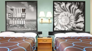 A hotel room with two beds, a wooden nightstand with a phone, and wall-mounted lamps. - Super 8 by Wyndham St. Augustine (St. Augustine)