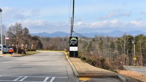 A road leading to a Mountain Inn with a signboard, a McDonald's, and a view of mountains in the background. - Dahlonega Mountain Inn (Dahlonega)