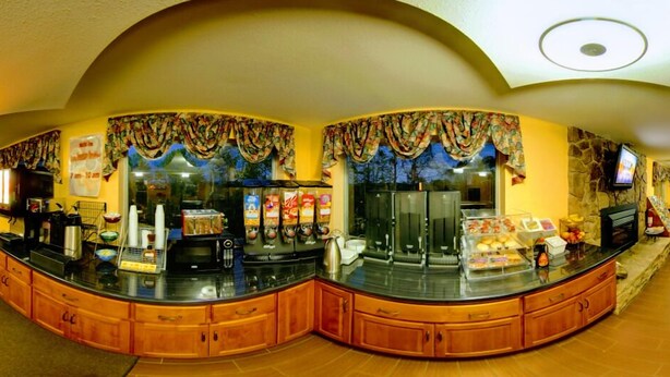 A breakfast bar with coffee machines, a microwave, and a TV. - Dahlonega Mountain Inn (Dahlonega)