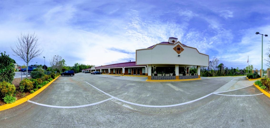 A parking lot leading to a building with a red roof and a yellow trim.