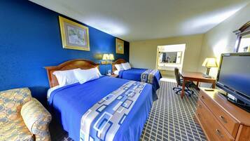 A hotel room with two beds, a desk, a television, and a bathroom visible through an open door.