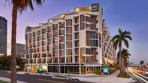 Un hôtel moderne à l’architecture imposante, avec plusieurs étages, sur lequel on peut voir un grand panneau « AC » au sommet.