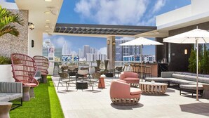 Un salon sur le toit avec des espaces de détente en plein air, un bar et une vue sur la ville.