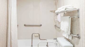 A bathroom with a shower, toilet, and grab bars.