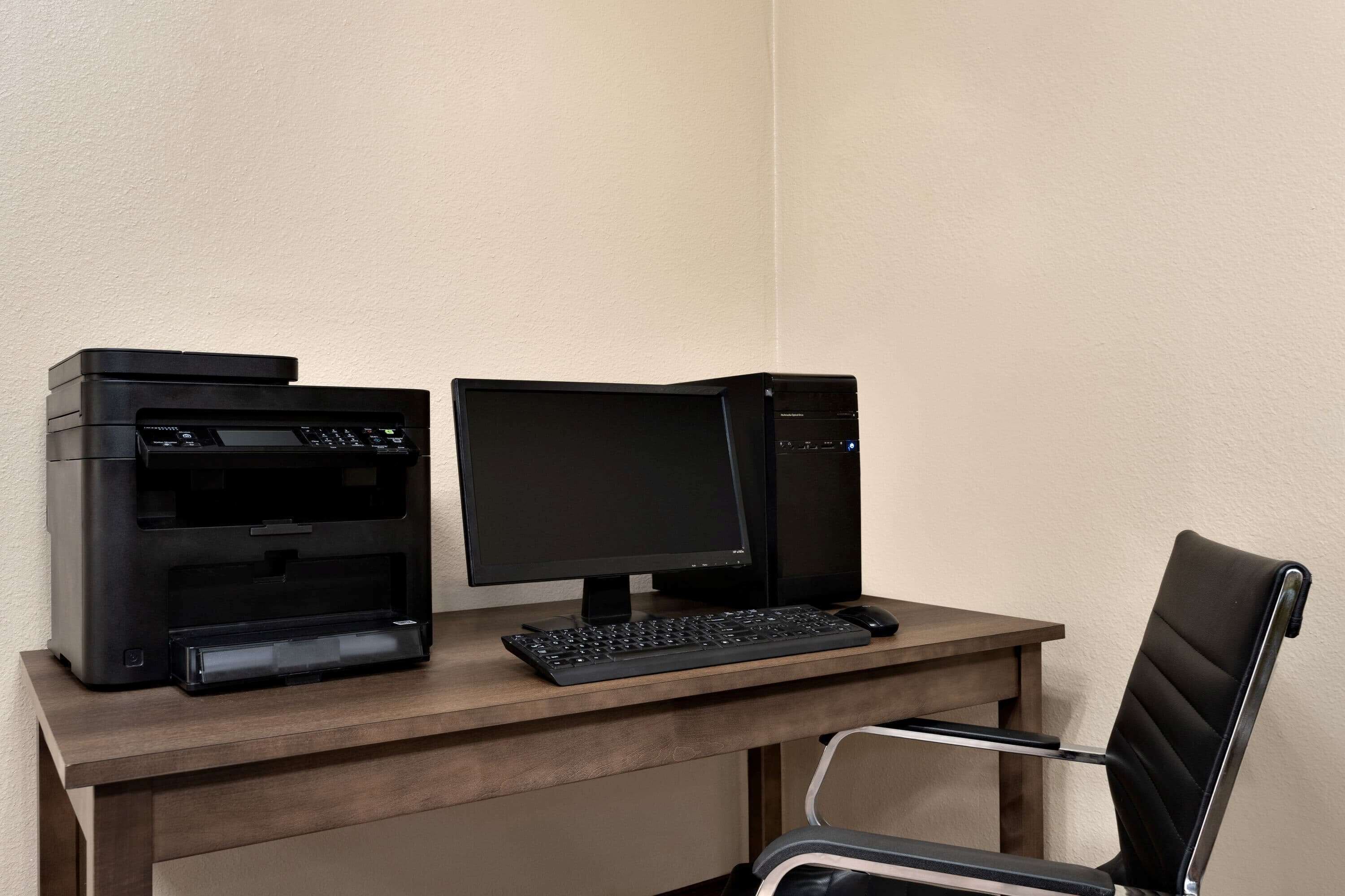 A desk with a printer, a monitor, and a keyboard.