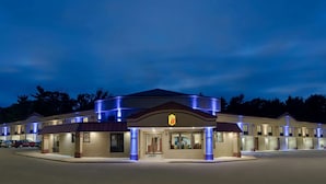 A motel with a central entrance, multiple rooms, and a parking area.