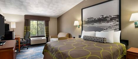 A hotel room with a large bed, a desk, a chair, a TV, and a window with curtains.