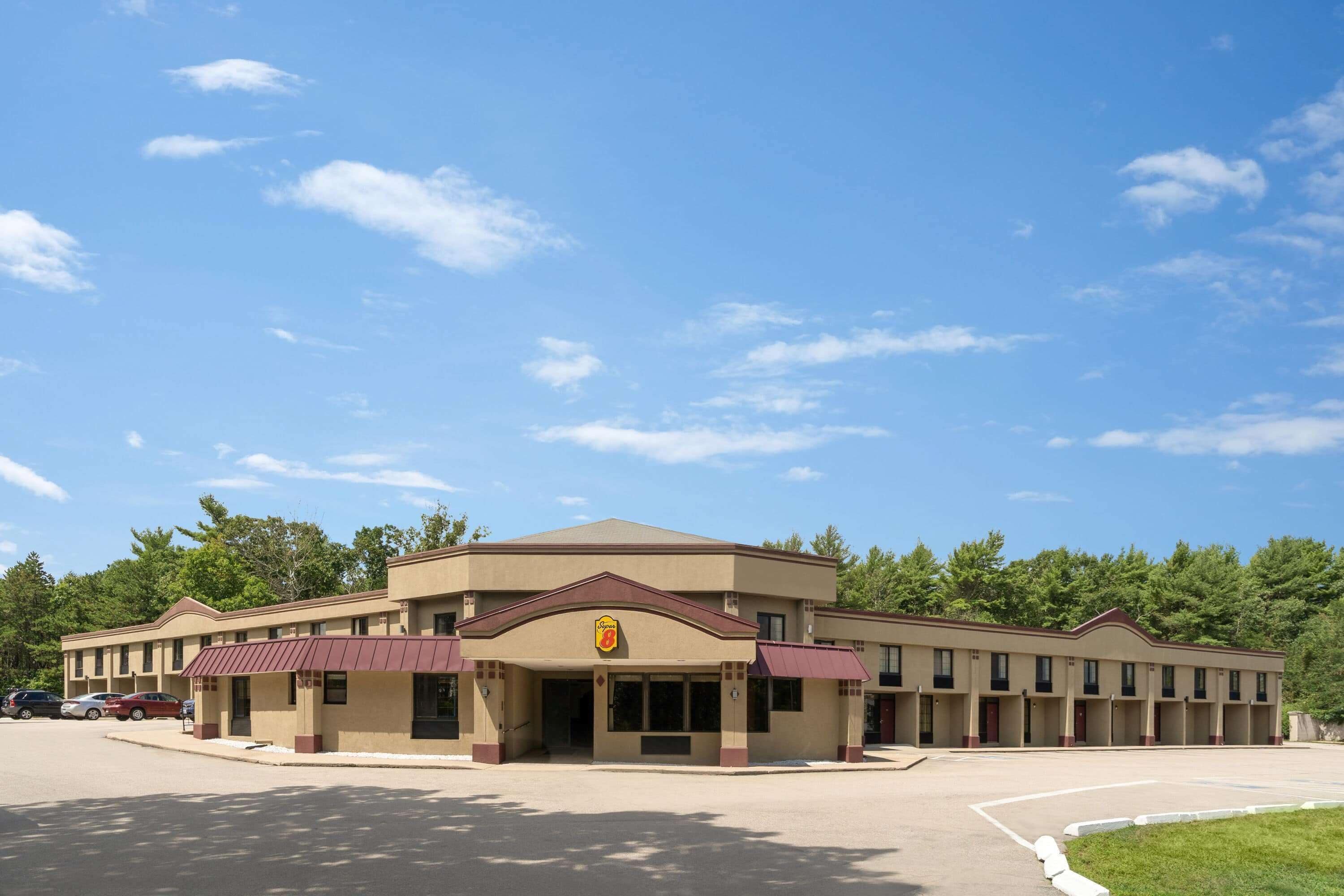 A motel with a central entrance, multiple rooms, and a parking lot.
