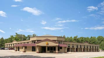A motel with a central entrance, multiple rooms, and a parking lot.