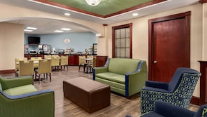 A lobby with a dining area, a reception desk, and a large wooden door.