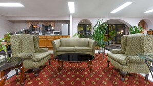 Eine Hotellobby mit einer Sofagarnitur, einem Couchtisch und einer Küchenzeile im Hintergrund.