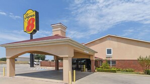 Ein Super 8 Hotel mit überdachter Eingangspartei, Backsteinfassade und blauem Himmel.