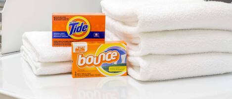 A stack of white towels and two detergent boxes on a white surface.