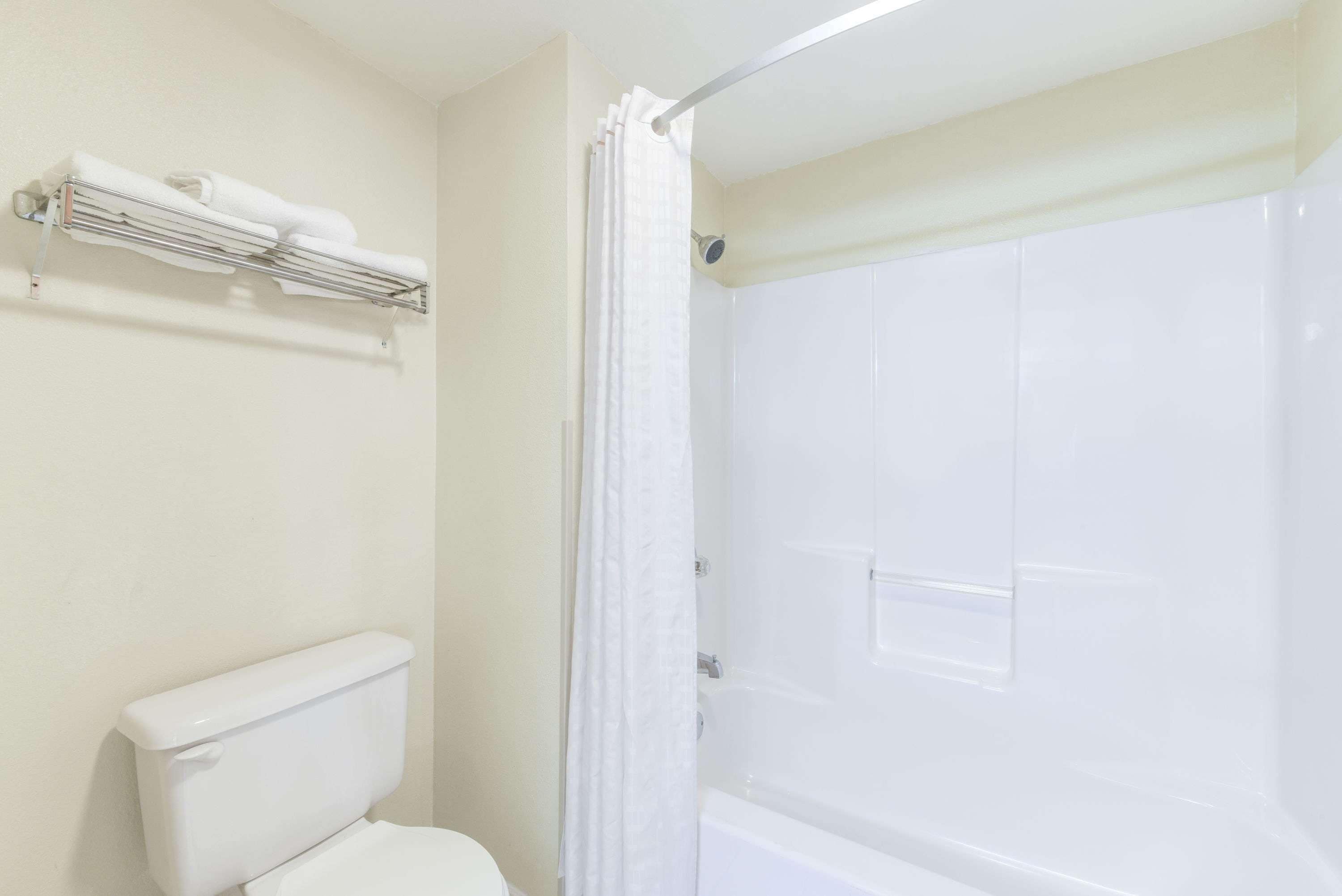 Une salle de bain comprenant des toilettes, une douche avec une porte en verre et un porte-serviettes.
