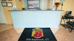 A reception desk with a framed welcome sign, a computer, and a phone. - Super 8 by Wyndham Old Saybrook (Old Saybrook)