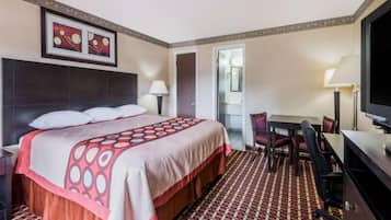 Habitación de hotel con cama, escritorio, silla, televisor y puerta que da a un baño.