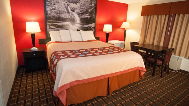 A hotel room with a large bed, two bedside tables with lamps, a desk, and a chair. - Super 8 by Wyndham Old Saybrook (Old Saybrook)