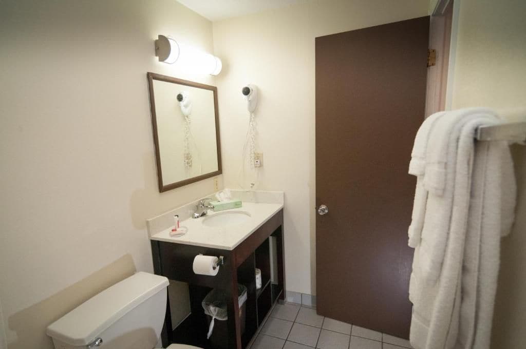 Un baño con inodoro, lavabo, espejo y toallero.