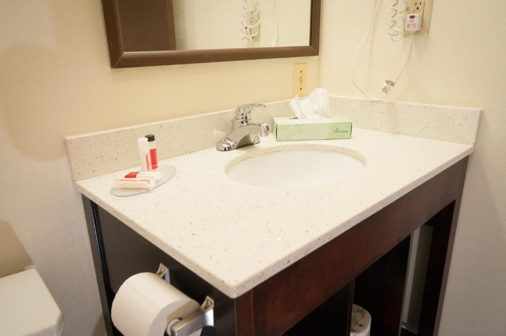 A bathroom with a white sink, a mirror, and a toilet.