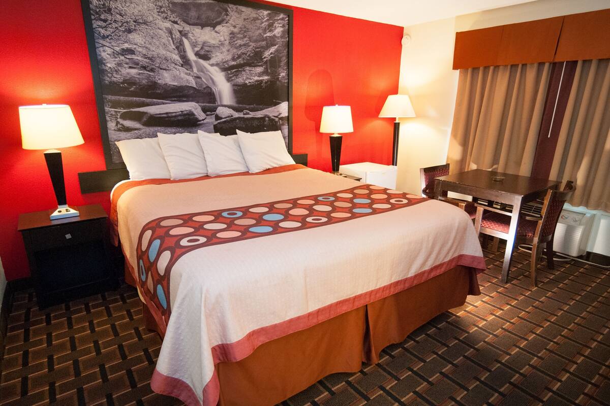 A hotel room with a large bed, two bedside tables with lamps, a desk, and a chair.