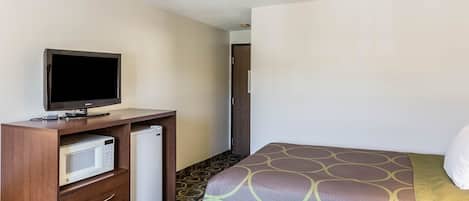 Una habitación de hotel con una cama, un televisor sobre una cómoda de madera, un microondas y un refrigerador.