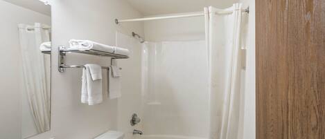 A bathroom with a bathtub, a toilet, a sink with a countertop, and a mirror.