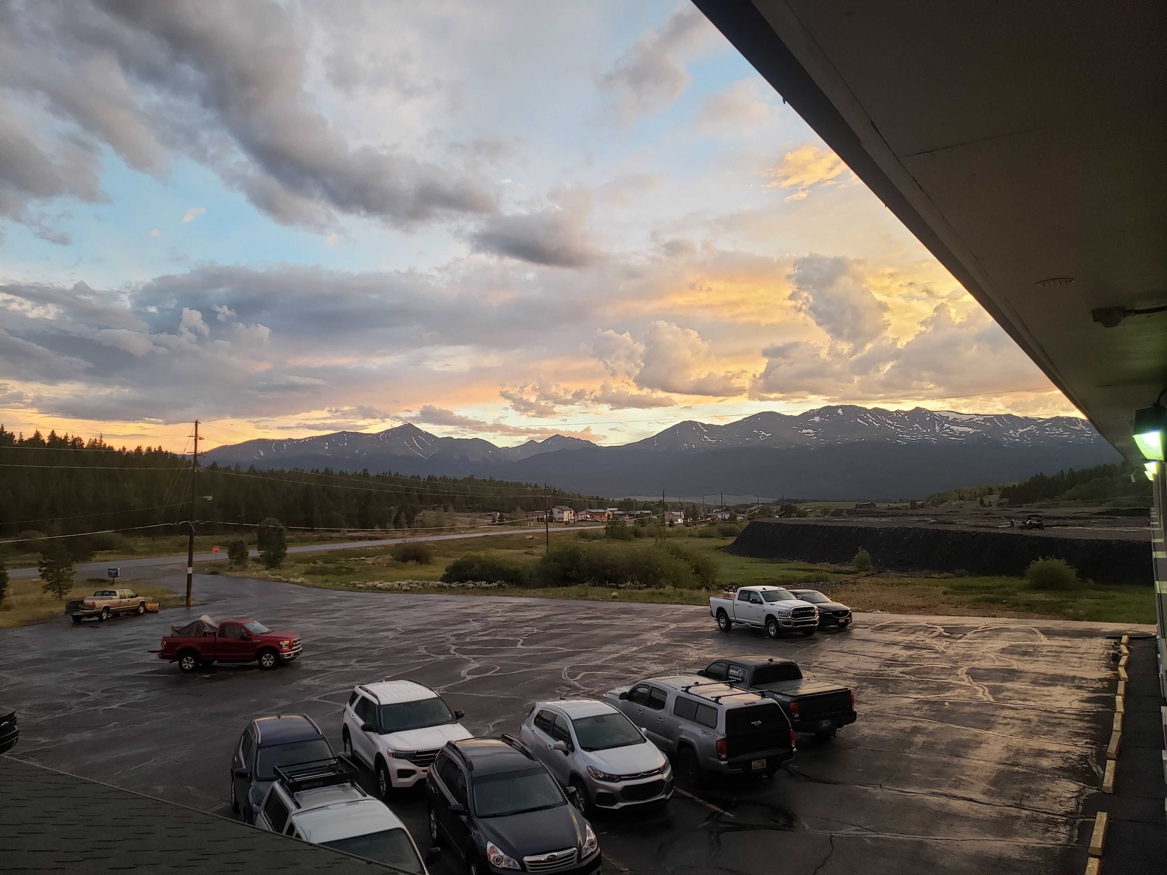 A parking lot with several cars and a mountainous landscape in the background.