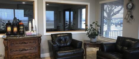A living room with a fireplace, two black leather chairs, a wooden cabinet, and a coffee station.