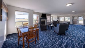 A spacious room with a large window, a fireplace, and a seating area with a blue patterned carpet. - Super 8 by Wyndham Jackson MN (Jackson)