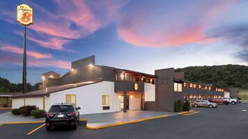 A Super 8 motel with a two-story structure, a parking lot, and a scenic sunset backdrop.