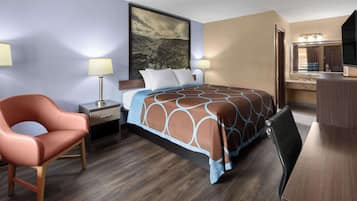 A hotel room with a bed, a desk, a chair, a nightstand, a lamp, and a painting on the wall.
