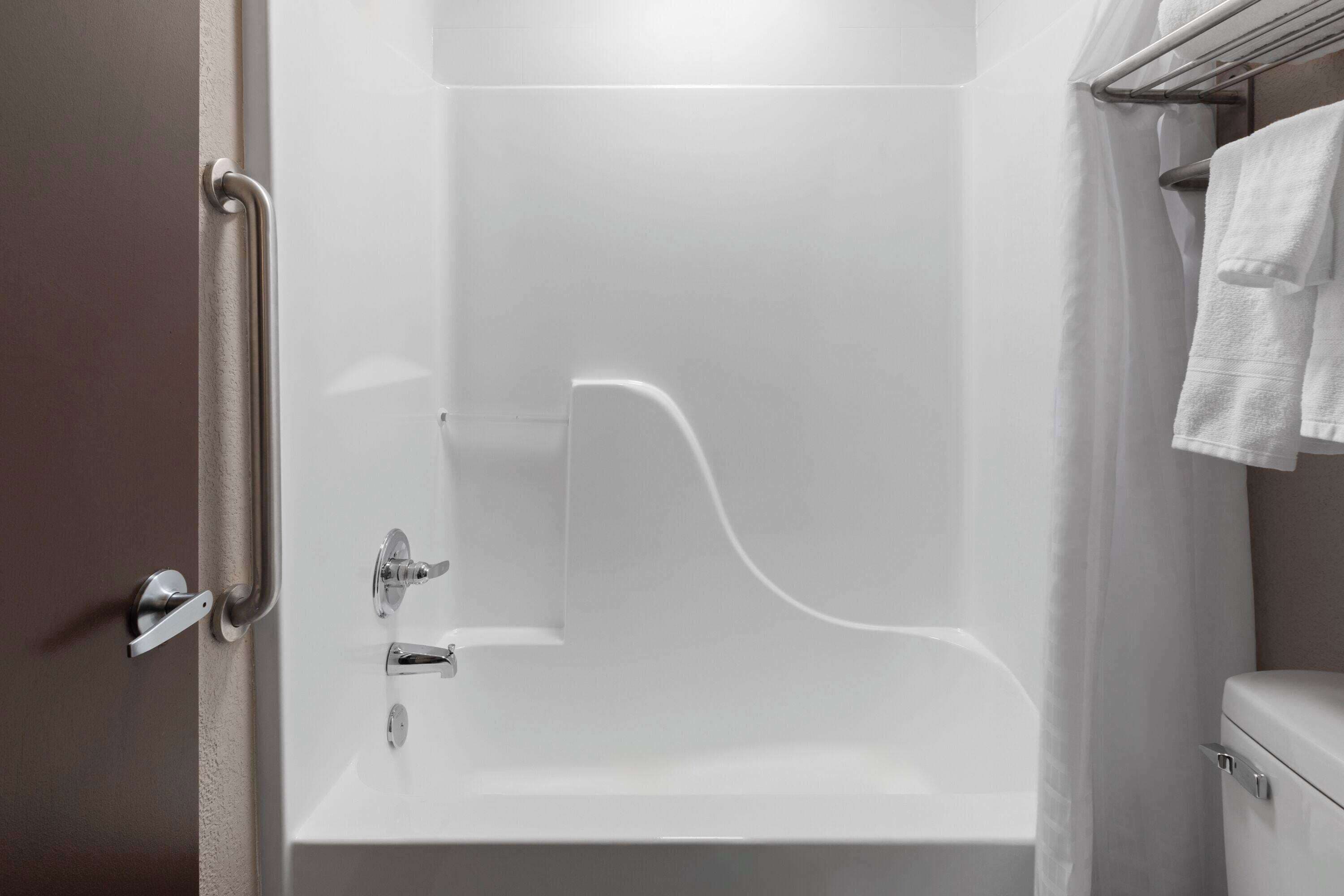 A bathroom with a white bathtub, a toilet, and a shower area.