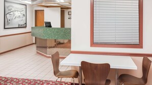 A reception area with a green counter, a white table, and two brown chairs. - Super 8 by Wyndham Shipshewana (Shipshewana)