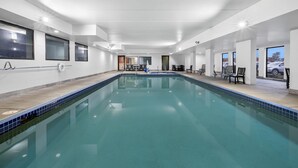 A large indoor swimming pool with clear blue water, surrounded by white walls and a tiled floor. - AmericInn by Wyndham Columbus Wisconsin (Columbus)