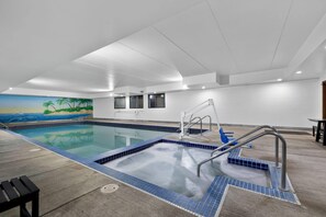 Ein Schwimmbecken mit einer gefliesten Kante, einer Metallleiter und einem Wandgemälde mit einer Strandansicht.