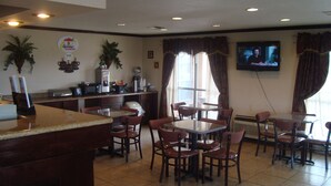 Ein Restaurant mit Barbereich, mehreren Tischen und Stühlen, einem an der Wand montierten Fernseher und einer Kaffeemaschine auf der Theke.