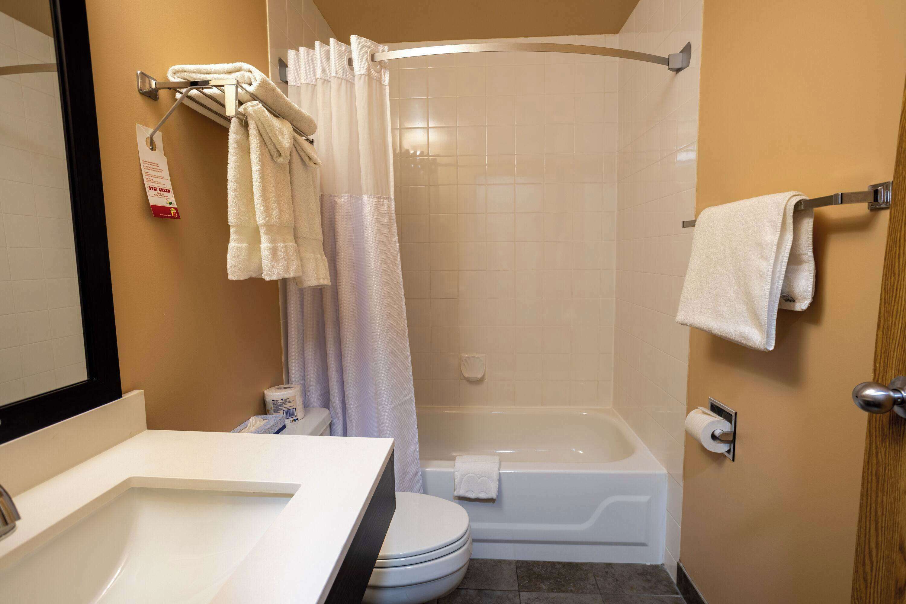 A bathroom with a toilet, sink, bathtub, and shower curtain.