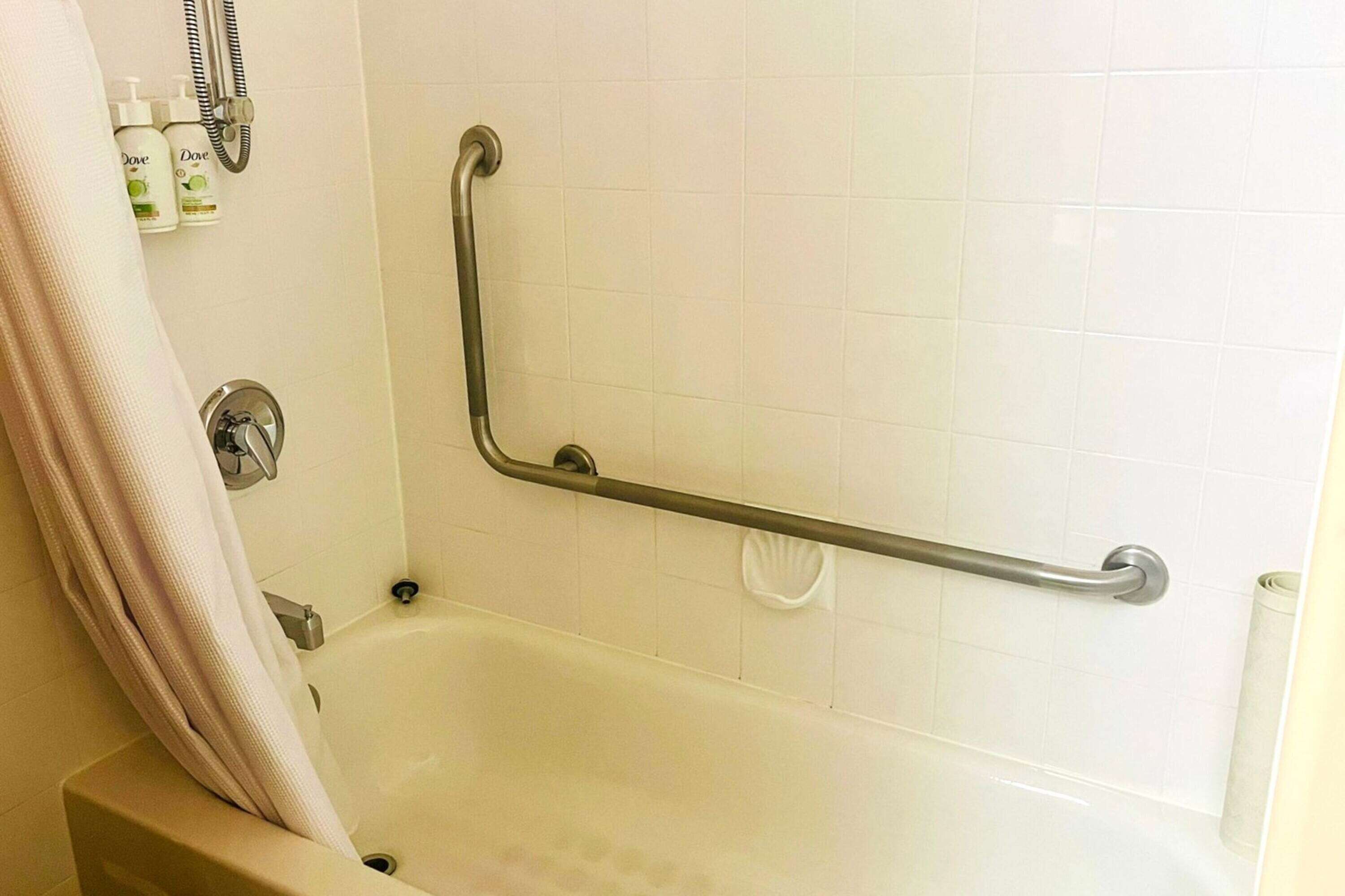 A bathroom with a bathtub, a shower, and a grab bar.