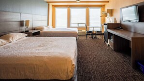 A hotel room with two beds, a desk, a television, and large windows. - Ramada by Wyndham Cranbrook (Cranbrook)