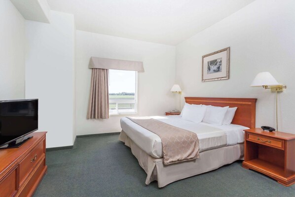 A hotel room with a bed, bedside lamps, a TV on a wooden cabinet, and a window with curtains.