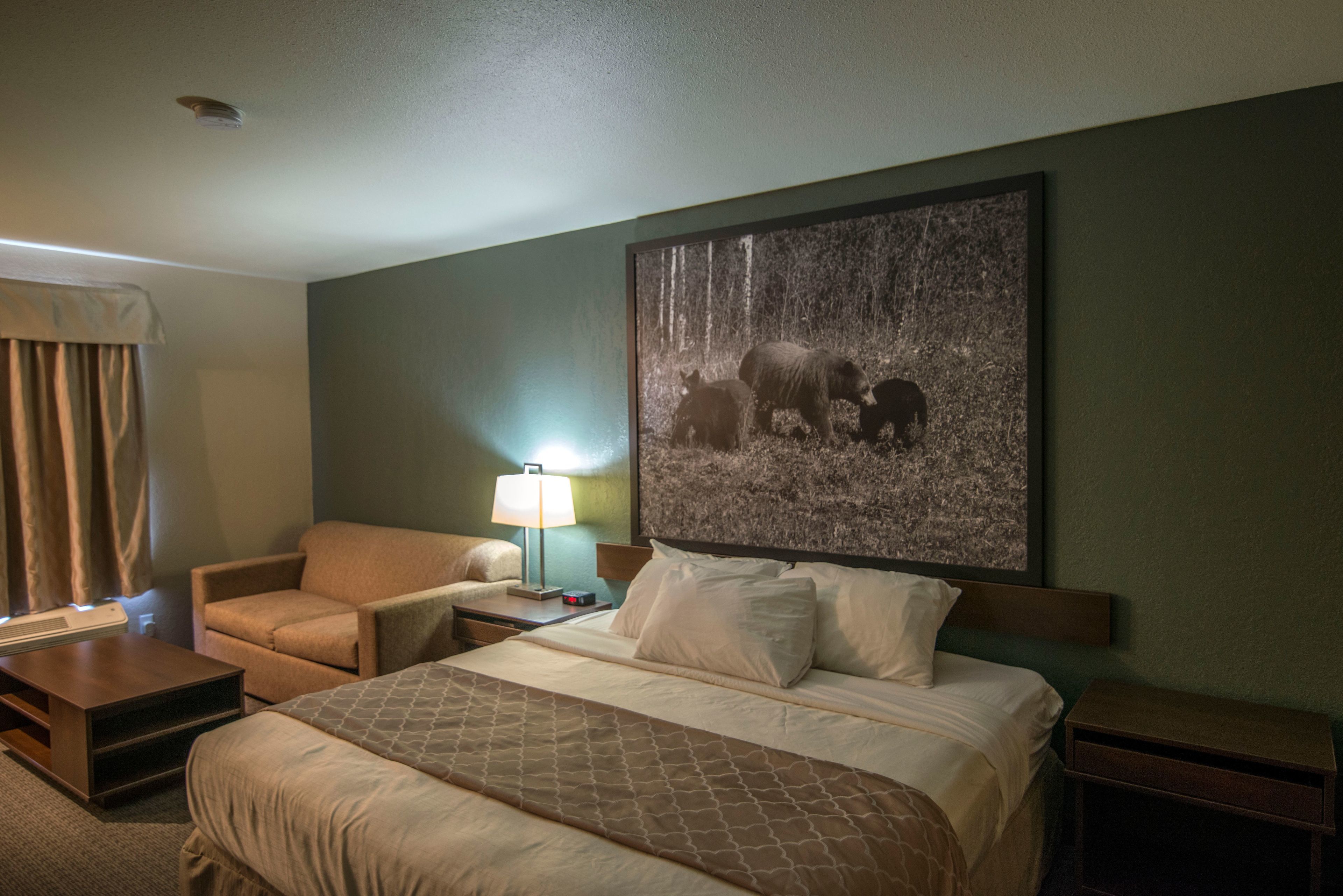 Een hotelkamer met een groot bed, een stoel, een nachtkastje en een wandlamp.