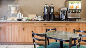 Eine Küche mit Holzausstattung, einer Granit-Arbeitsplatte, einer Kaffeemaschine und einem Kühlschrank.